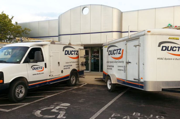 A DUCTZ company truck and trailer parked in front of a commercial building.