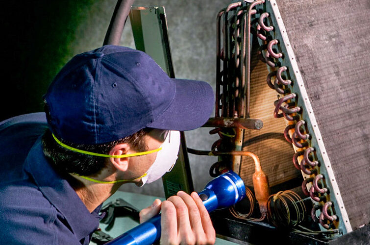 A DUCTZ technician performing service on a condenser coil unit.