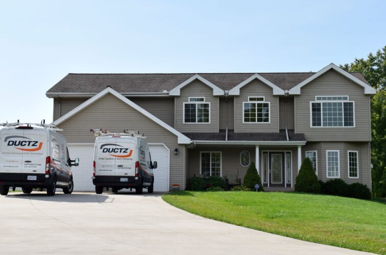 Two DUCTZ company vans parked on the driveway of a residential home.