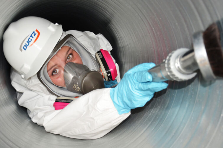 A DUCTZ technician performing service on a commercial air vent.