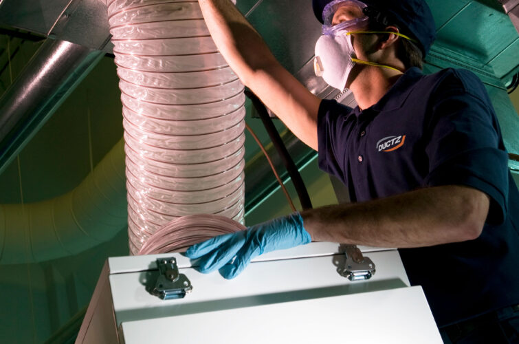 A DUCTZ technician performing service on a commercial air vent.
