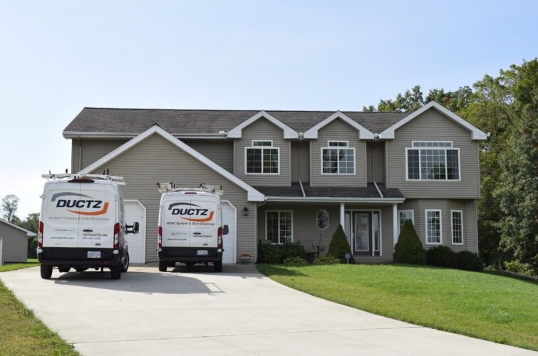 Two DUCTZ company vans parked in the driveway of a residential home.