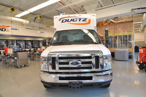 Frontside view of a DUCTZ commercial truck parked inside a garage.